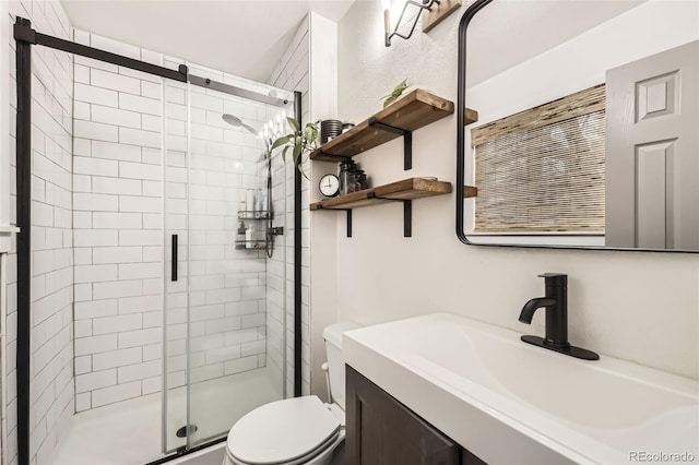 bathroom featuring toilet, a shower with shower door, and vanity