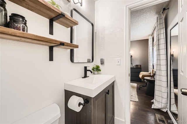 bathroom with vanity, toilet, a textured ceiling, and wood-type flooring