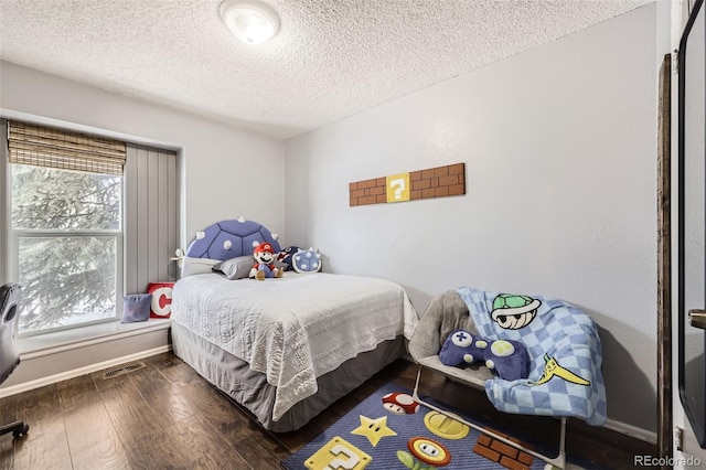 bedroom with dark hardwood / wood-style floors, a textured ceiling, and multiple windows