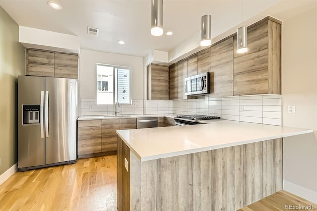 kitchen featuring stainless steel appliances, a sink, visible vents, backsplash, and modern cabinets