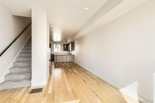 interior space featuring recessed lighting, visible vents, light wood-type flooring, baseboards, and stairs