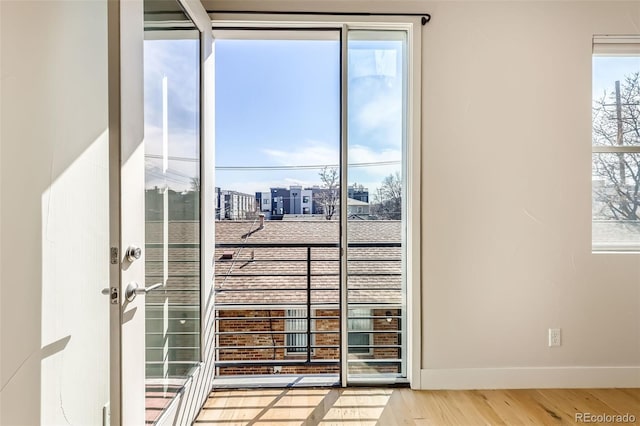 doorway to outside with a healthy amount of sunlight, baseboards, and wood finished floors