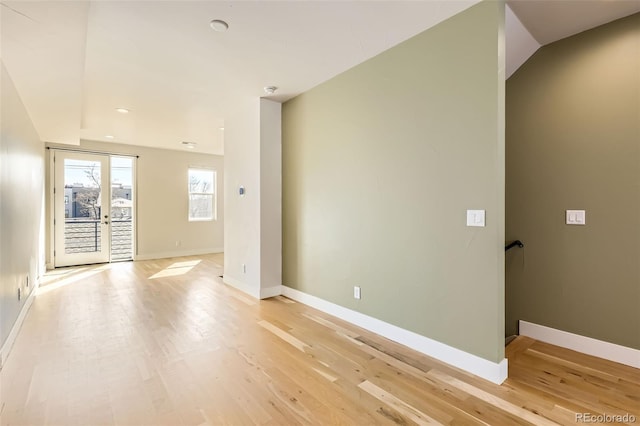 empty room with french doors, baseboards, and light wood finished floors