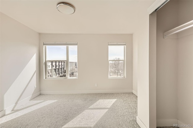 unfurnished bedroom featuring carpet floors, multiple windows, and baseboards