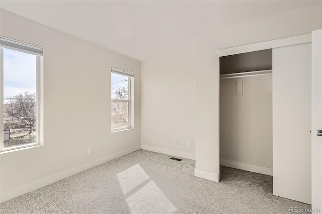 unfurnished bedroom with carpet, a closet, visible vents, and baseboards