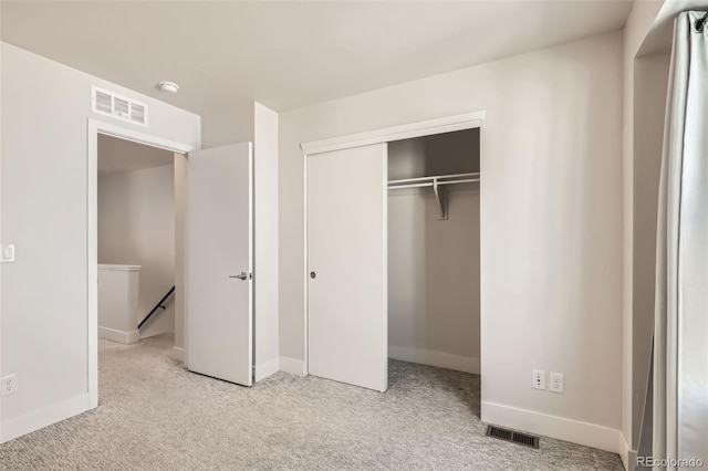 unfurnished bedroom with carpet floors, a closet, and visible vents