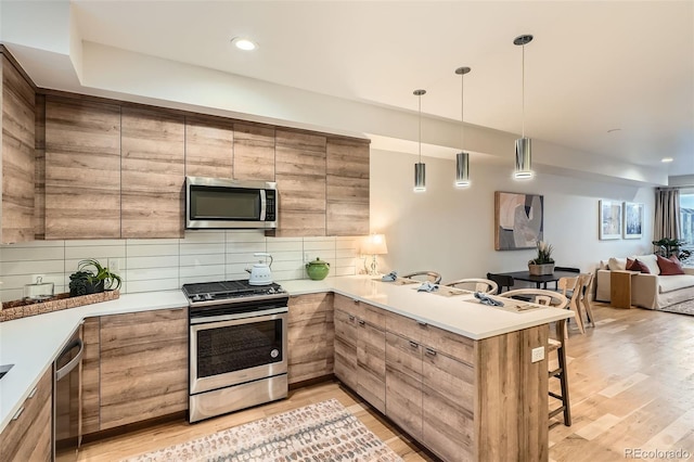 1810 Irving St Unit 4, Denver, CO 80204 - kitchen featuring light wood-style flooring, open floor plan, a kitchen breakfast bar, tasteful backsplash, and appliances with stainless steel finishes