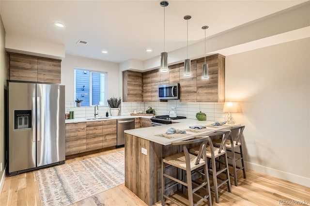 1810 Irving St Unit 4, Denver, CO 80204 - kitchen featuring a peninsula, stainless steel appliances, brown cabinets, and a sink