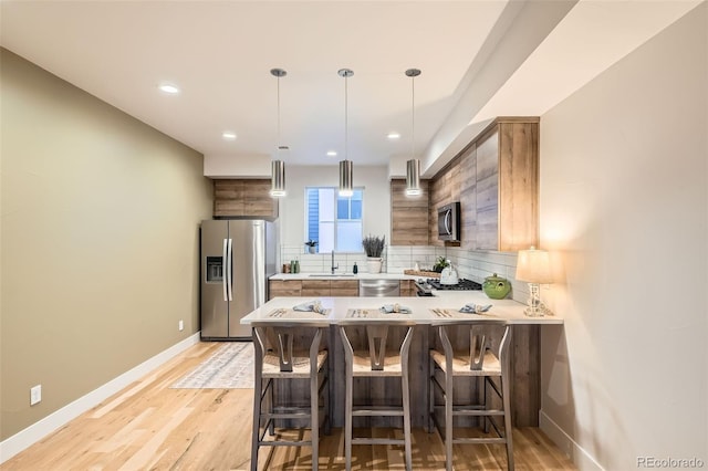 1810 Irving St Unit 4, Denver, CO 80204 - kitchen with a sink, stainless steel appliances, a kitchen breakfast bar, backsplash, and light countertops