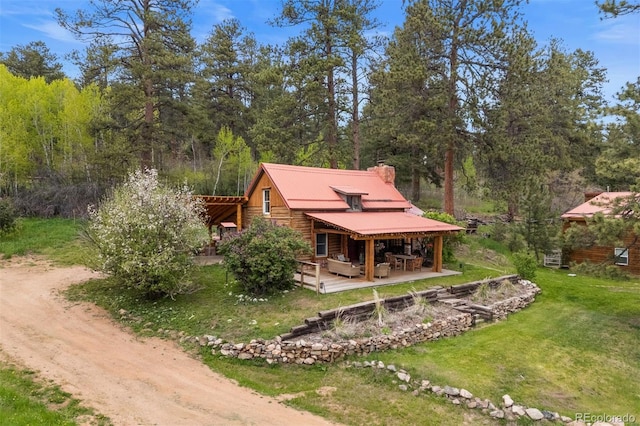 245 N County Highway 67, Sedalia, CO 80135 - view of front of house featuring a front lawn, a metal roof, a patio, a chimney, and a wooden deck