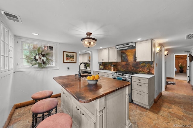 245 N County Highway 67, Sedalia, CO 80135 - kitchen featuring stainless steel range with gas stovetop, exhaust hood, arched walkways, a kitchen island with sink, and light stone finish flooring
