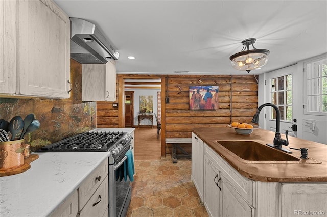 245 N County Highway 67, Sedalia, CO 80135 - kitchen with stainless steel gas range, log walls, range hood, a kitchen island with sink, and decorative backsplash