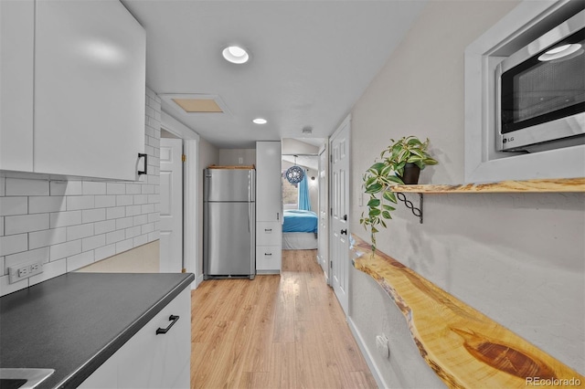 245 N County Highway 67, Sedalia, CO 80135 - kitchen with appliances with stainless steel finishes, light wood-style floors, white cabinets, dark countertops, and decorative backsplash