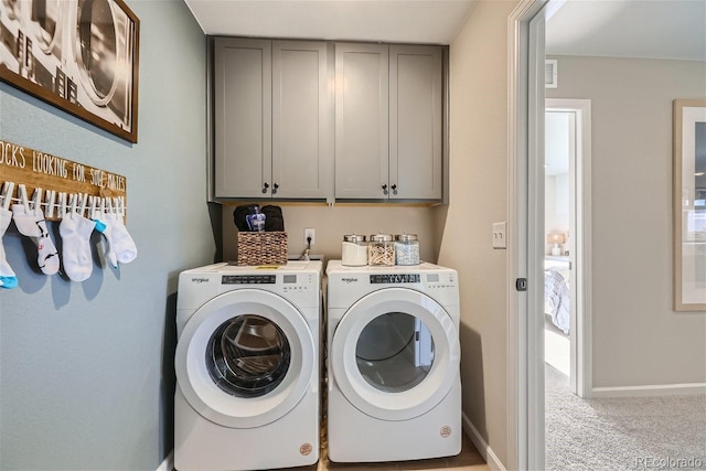 washroom with cabinets, light carpet, and washing machine and clothes dryer