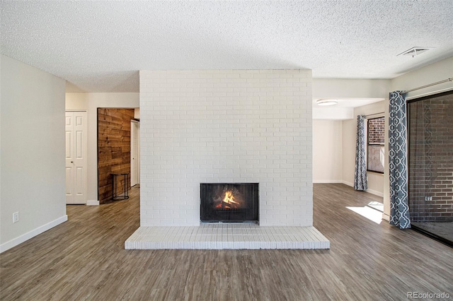 500 Manhattan Dr Unit B1, Boulder, CO 80303 - unfurnished living room featuring wood finished floors, baseboards, a textured ceiling, and a brick fireplace