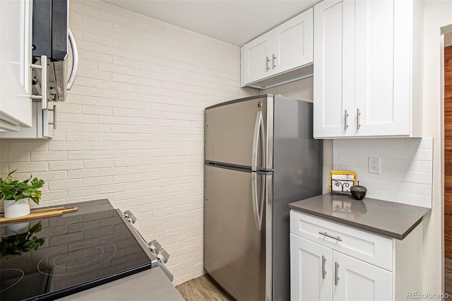 500 Manhattan Dr Unit B1, Boulder, CO 80303 - kitchen with freestanding refrigerator, dark countertops, white cabinetry, decorative backsplash, and brick wall