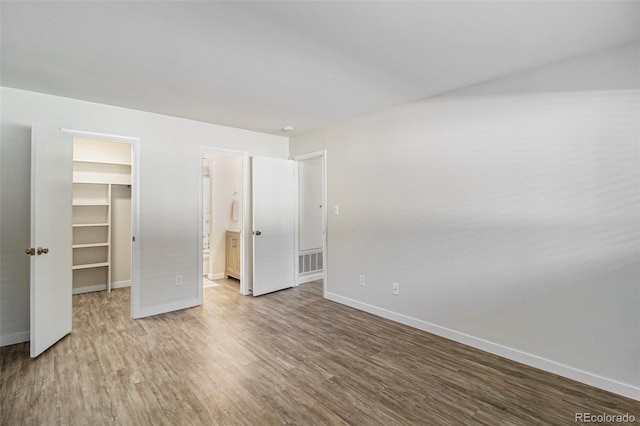 500 Manhattan Dr Unit B1, Boulder, CO 80303 - unfurnished bedroom with a spacious closet, wood finished floors, baseboards, a closet, and connected bathroom