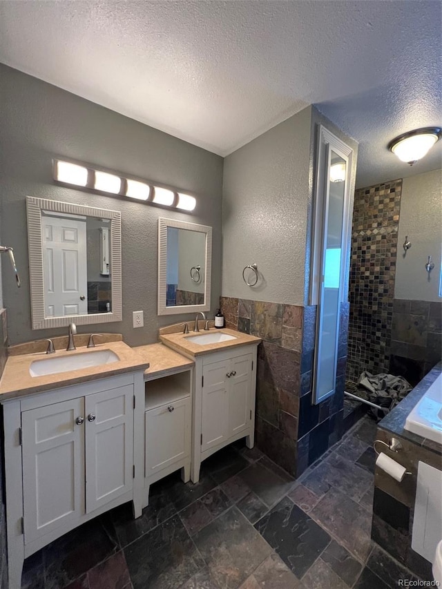 bathroom featuring a bath, a textured ceiling, tile flooring, and dual vanity