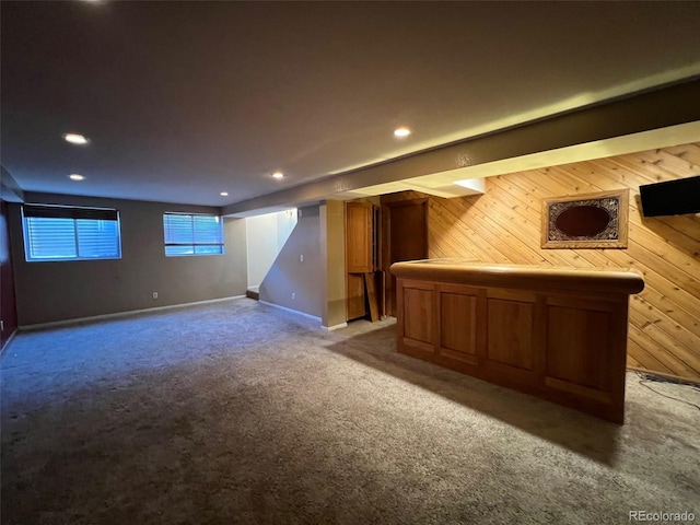 basement featuring light carpet and wooden walls