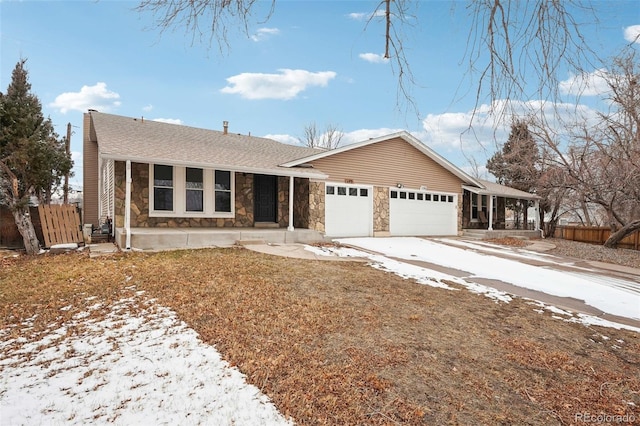 ranch-style home with roof with shingles, an attached garage, fence, stone siding, and driveway