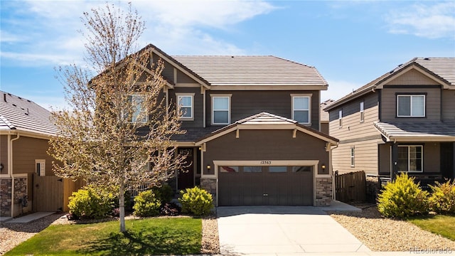 craftsman-style home featuring a garage, fence, stone siding, a gate, and driveway