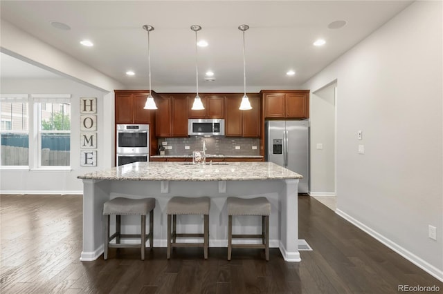 kitchen with a breakfast bar area, appliances with stainless steel finishes, an island with sink, and tasteful backsplash