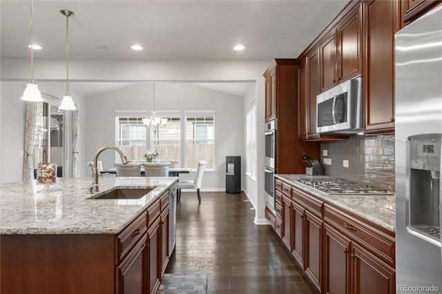 kitchen featuring dark wood-style flooring, appliances with stainless steel finishes, a sink, a chandelier, and backsplash