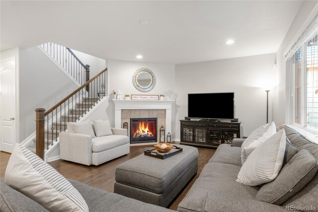 living room featuring stairs, recessed lighting, a tiled fireplace, and wood finished floors