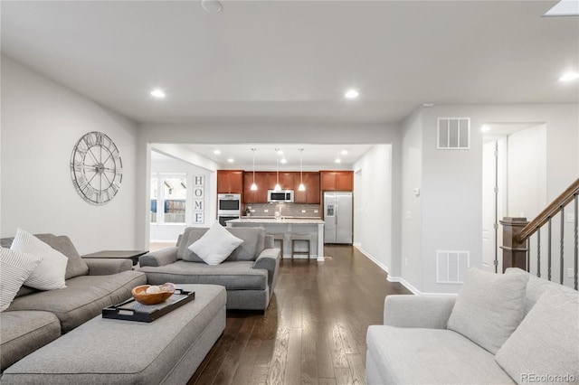 living area with dark wood-type flooring, recessed lighting, stairs, and visible vents