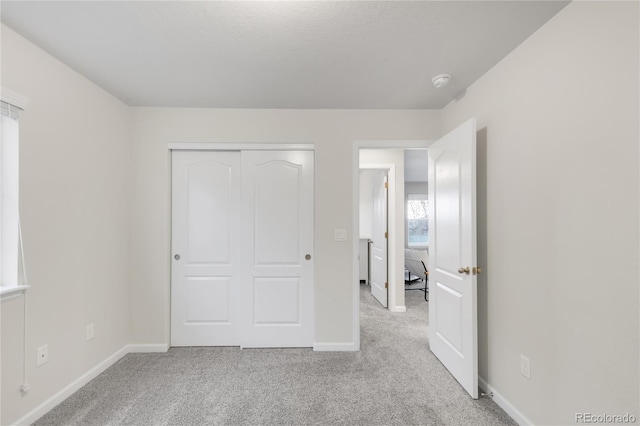 unfurnished bedroom featuring carpet floors, baseboards, and a closet