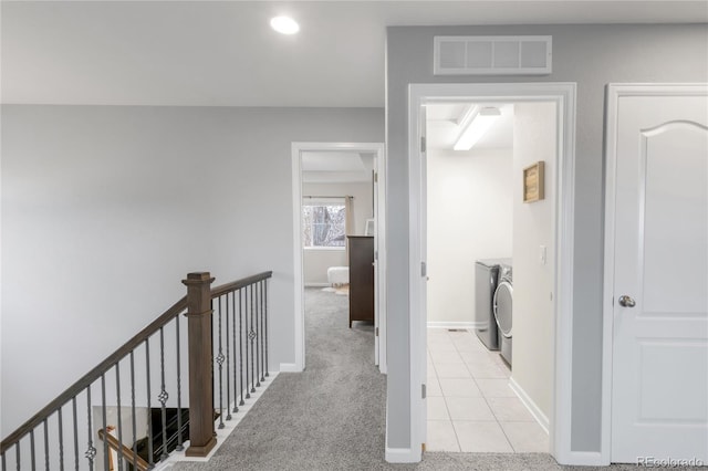 corridor with visible vents, light tile patterned floors, baseboards, an upstairs landing, and washer and dryer
