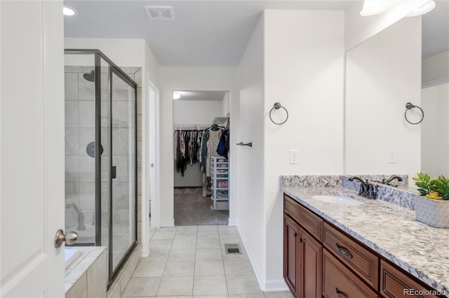 full bathroom featuring vanity, a spacious closet, a shower stall, and visible vents