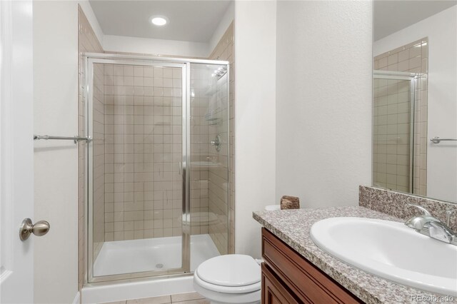 bathroom featuring toilet, recessed lighting, a shower stall, and vanity