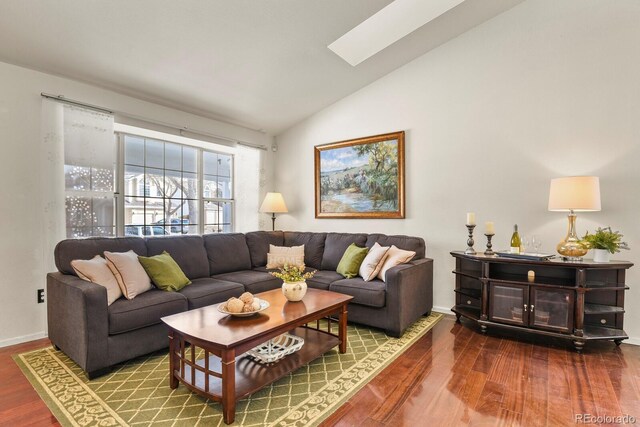 living room featuring hardwood / wood-style flooring and vaulted ceiling with skylight