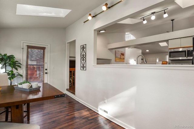 dining room featuring sink, dark wood-type flooring, lofted ceiling with skylight, and a healthy amount of sunlight