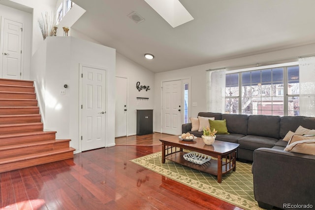 living room with hardwood / wood-style flooring and vaulted ceiling with skylight