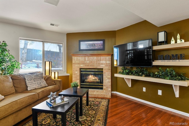 living room with a brick fireplace and dark hardwood / wood-style flooring