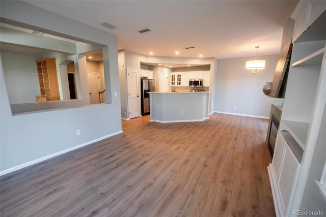 unfurnished living room with baseboards, visible vents, wood finished floors, and recessed lighting