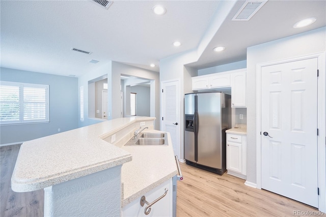 kitchen featuring white cabinets, visible vents, a sink, and stainless steel refrigerator with ice dispenser