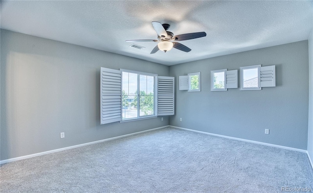 unfurnished room featuring carpet floors, visible vents, a ceiling fan, a textured ceiling, and baseboards