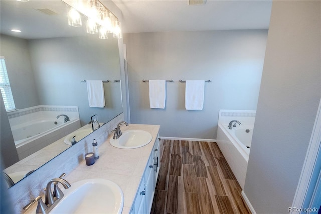 bathroom with double vanity, wood finish floors, a sink, and a bath