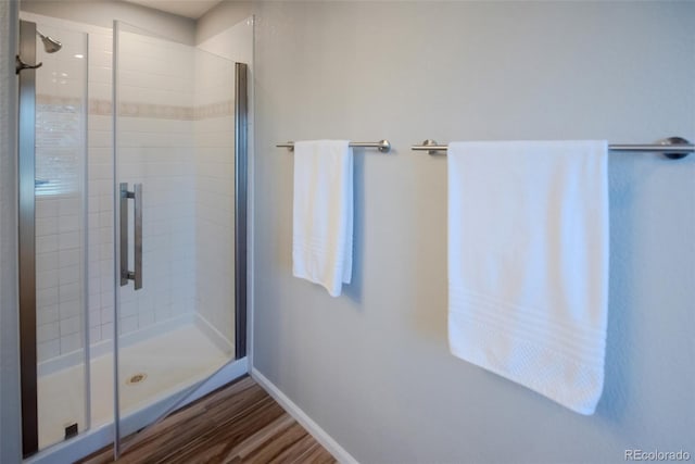 full bath with a stall shower, baseboards, and wood finished floors