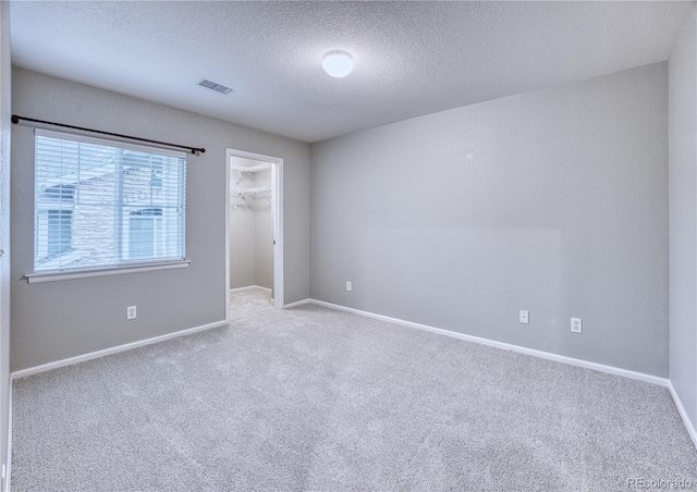 empty room with carpet, visible vents, and baseboards