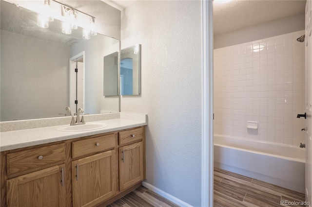 bathroom with wood finish floors, shower / bath combination, a textured wall, and vanity