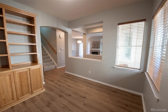 interior space featuring arched walkways, built in shelves, baseboards, stairway, and dark wood finished floors