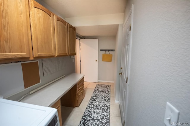 interior space featuring light tile patterned floors, laundry area, a textured wall, and washer / dryer