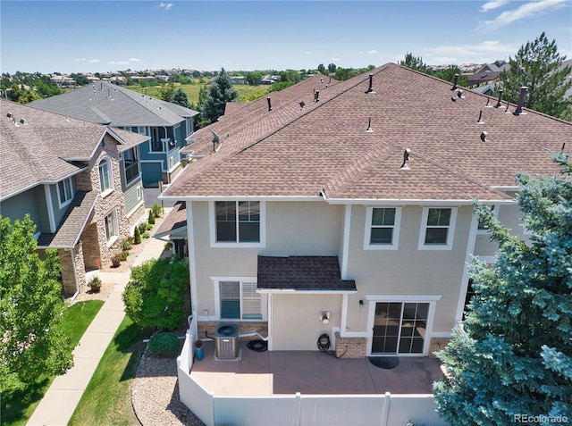 rear view of house featuring roof with shingles, a patio, brick siding, central AC, and fence