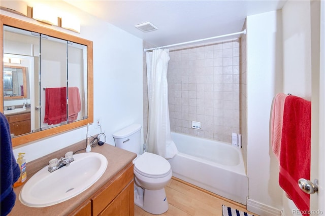 bathroom with visible vents, shower / bath combo with shower curtain, toilet, wood finished floors, and vanity