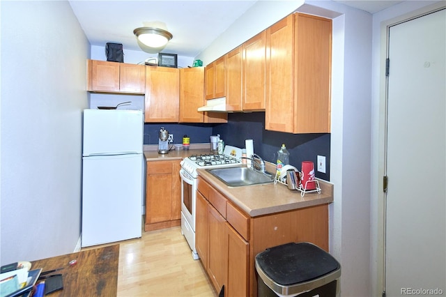 kitchen featuring a sink, light wood-type flooring, white appliances, and light countertops