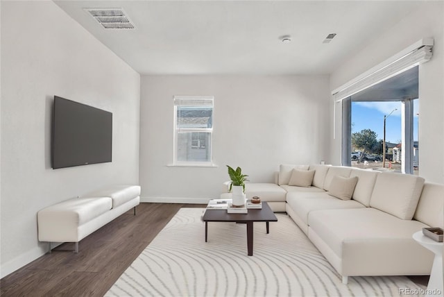 living area with plenty of natural light, visible vents, and wood finished floors